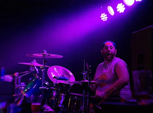 Joe Saad looking at camera from the side playing drums at Bleacher's Bar in Bristol, CT