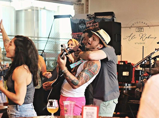 Mike Angeli and Joe Scovill hugging during performance at Two Roads Brewing in Stratford, CT